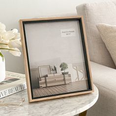 a photo frame sitting on top of a table next to a vase with flowers