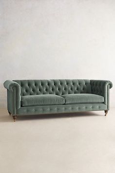 a green couch sitting on top of a white floor next to a wall and chair