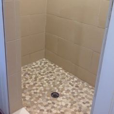 a bathroom with a shower stall and tiled flooring on the walls, along with a toilet in the corner