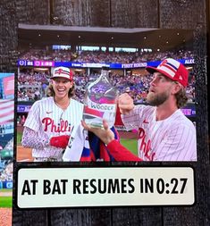 a baseball player holding a trophy in front of a tv screen with the caption at bat resumes in 027