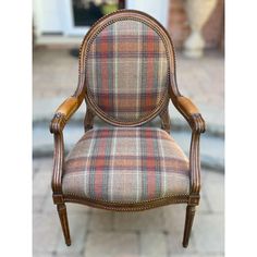 an old chair is upholstered with wood and plaid fabric