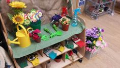 flowers and gardening tools are sitting on a shelf in a store display case, along with other garden items