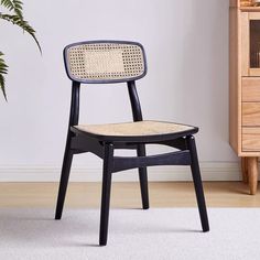 a black chair sitting on top of a white rug next to a wooden dresser and potted plant