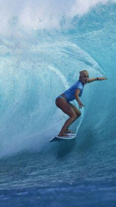 a woman riding a wave on top of a surfboard