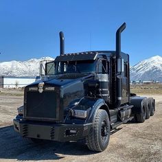 a large black truck parked on top of a dirt field