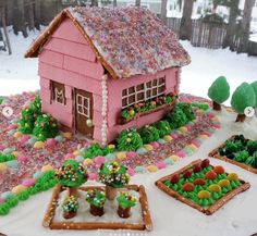 there is a cake made to look like a pink house with trees and flowers on it