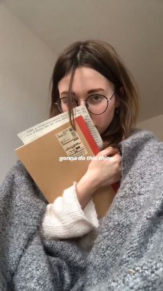 a woman wearing glasses is holding a book