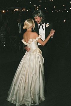 a man in a tuxedo standing next to a woman