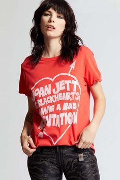 a woman wearing an orange shirt with the words joan jettt black hearts have a bad situation on it