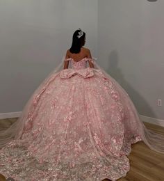 a woman in a pink ball gown looking at the wall