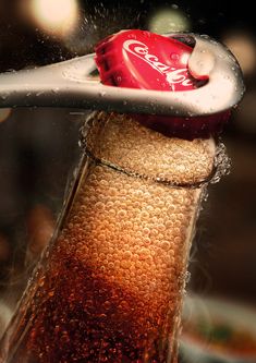 a close up of a soda bottle with water splashing on it's cap