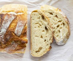 two pieces of bread sitting on top of a piece of wax paper next to each other