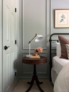 a bed room with a neatly made bed and a lamp on the end table next to it