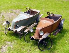 two old fashioned pedal cars sitting in the grass