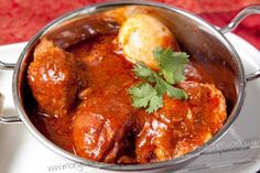 a pot filled with meat and garnish on top of a white plate