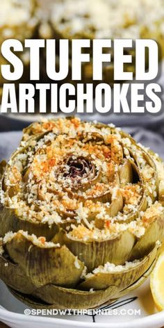 stuffed artichokes on a white plate with lemon wedges in the background