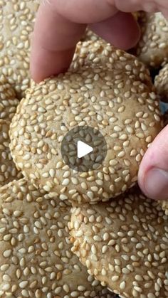 sesame seed cookies are being held by someone's hand with a tiny button on the top