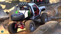 an off - road vehicle with two green bottles on it's tires driving through rocks