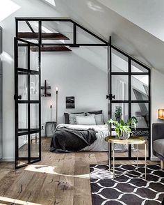 an attic bedroom with white walls and wood flooring is furnished with gray furniture, black accents