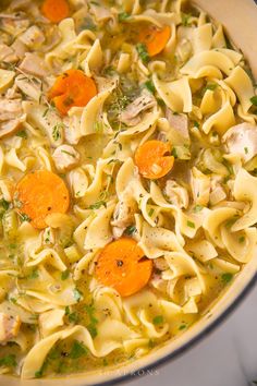 chicken noodle soup with carrots and parsley in a pot