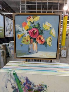 a painting on display in a store with other paintings behind it and an easel next to it