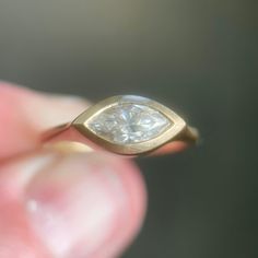 a close up of a person's hand holding a ring with a diamond in it