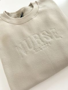 Personalized Nurse Sweatshirt! RN Crewneck Unisex Swestshirt for Nurse or New Grad Nurse Gift!  Perfect for any occasion or as a gift to say thank you to your favorite medical professional!   For personalization: Enter what year you were established! Super Soft and Comfy!  Gildan 50/50 Unisex Crewneck. Listing image is Sand sweatshirt with Ivory thread. Color may slightly vary depending on what kind of device you are viewing on. Please allow 3-5 business days for processing as these are made to order. I ship through the USPS. Care: For best results, Turn Inside Out! Wash on gentle cycle. Air Dry. Iron as needed.  No returns due to health and safety reasons.  Unisex Sizing. Please refer to Size Chart to ensure a perfect fit. Nurse Embroidery, Nursing Motivation, New Grad Nurse, Nurse Crewneck, Cute Scrubs, Nurse Sweatshirt, Embroidered Crewneck, Embroidered Sweatshirt, Personalized Embroidered