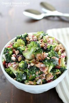 a white bowl filled with broccoli salad on top of a wooden table