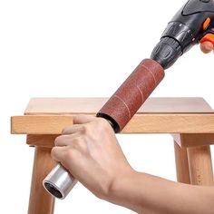 a person using a hammer to attach a piece of wood on top of a stool