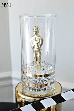 a glass with a gold statue on top of it next to a black and white checkered table