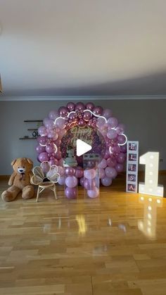 a teddy bear sitting in front of a balloon arch