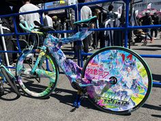 a colorful bicycle parked in front of a blue fence with graffiti on the rims