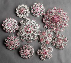 some pink and white brooches are laying on a gray surface with other items