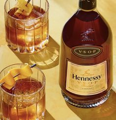 a bottle of hennessy veuver next to two glasses filled with drinks