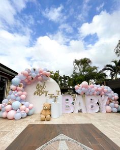 there is a baby shower sign with balloons and teddy bears on the front lawn,