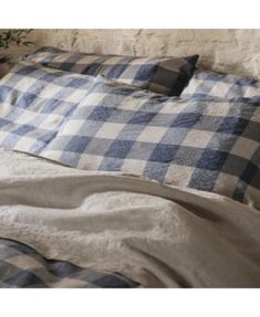 a blue and white checkered comforter on a bed with pillows in front of it