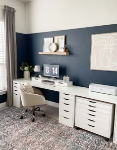 a white desk sitting in front of a window next to a wall with pictures on it