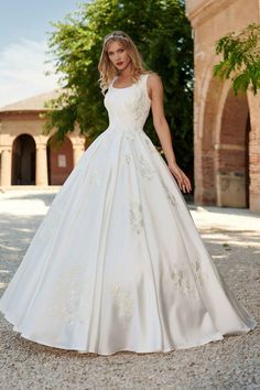 a woman in a white wedding dress posing for the camera with her hand on her hip