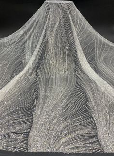 an artistic drawing made with white thread on black paper, depicting the shape of a mountain