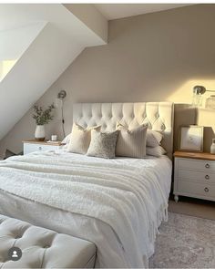 a white bed sitting under a slanted ceiling in a bedroom next to a window