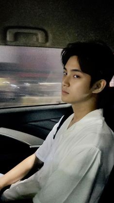 a young man sitting in the driver's seat of a car