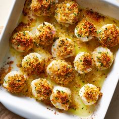 a white casserole dish filled with scallops covered in parmesan cheese