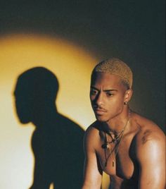 a man with no shirt sitting in front of a shadow