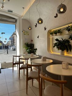 the inside of a restaurant with tables, chairs and potted plants on the wall