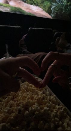 two people reaching for food in front of a large screen