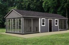 a dog kennel in the middle of a grassy area with trees and grass behind it