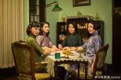 four women sitting at a table in an old - fashioned dining room with green walls