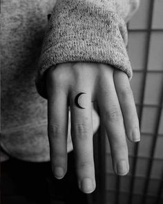 a person's hand with a small crescent tattoo on the middle finger, and a half moon tattooed on the other hand