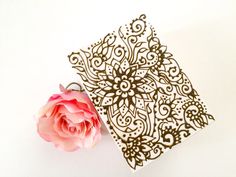 a pink flower sitting next to a piece of paper with an intricate design on it