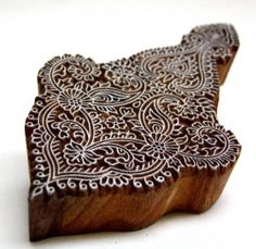 an intricately carved wooden coaster on a white surface with a pattern in the middle